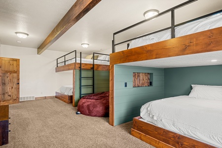 Your group's spacious bunk room blends mountain-cabin charm with modern comfort. Climb into your cozy nook under exposed beams, or unwind on the bean bag after a day of adventure.