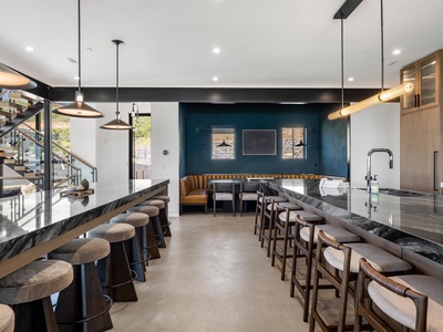 Gather friends and family in this sleek, modern space featuring stylish bar seating, a cozy banquette nook, and dramatic lighting that sets the perfect mood for socializing.