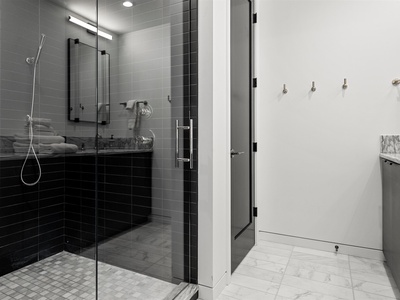 Step into your sleek glass-enclosed shower with dual controls and a rainfall head, then dry off in a crisp, modern bathroom designed for your comfort.