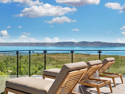 The property's terrace offers panoramic views of a stunning lake and mountain backdrop, a serene setting ideal for peaceful relaxation throughout the day.