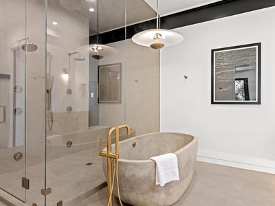 Sink into this sculptural stone tub with gleaming gold fixtures, or refresh in your spacious glass-enclosed shower. Elegant design meets luxurious comfort in your private spa-like retreat.