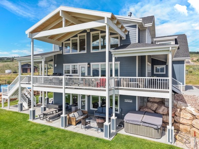 Modern vacation rental with expansive decks and outdoor living spaces set against rolling hills and open countryside.