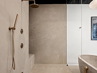 A sleek walk-in shower with rainfall and handheld fixtures invites you to unwind under soothing streams. The minimalist design and polished concrete walls create your personal spa sanctuary.