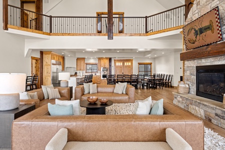 You'll love gathering here in this stunning open-concept great room. Vaulted ceilings, exposed wood beams, and a cozy stone fireplace create a warm mountain atmosphere, while spacious seating and a full kitchen invite everyone to relax together.
