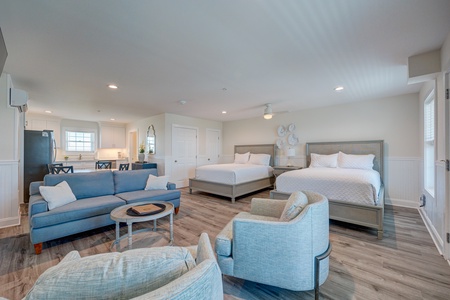Your spacious suite blends bedroom comfort with living room relaxation, featuring two cozy beds and modern coastal-inspired furnishings.