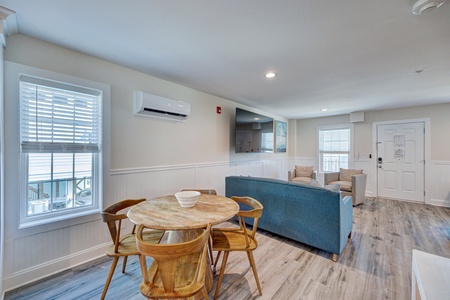 Relax in your stylish open-plan living space featuring warm wood dining table, comfortable seating, and modern amenities for your perfect getaway.