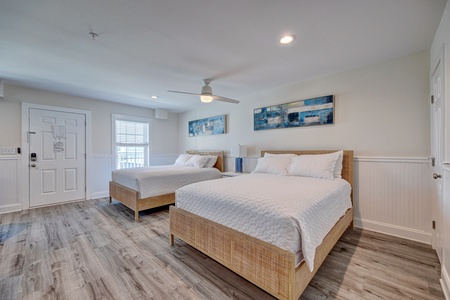Drift into peaceful sleep in your spacious bedroom featuring two comfortable beds with crisp linens and coastal artwork.