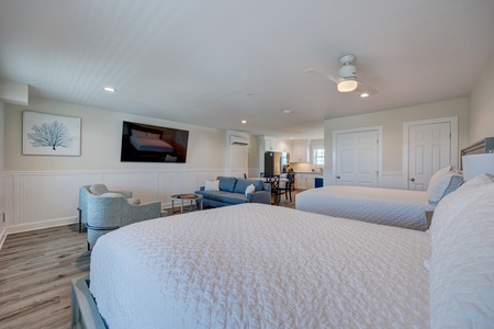 Relax in your spacious suite with plush beds, cozy seating area, and open-concept kitchen—perfect for unwinding after beach adventures.