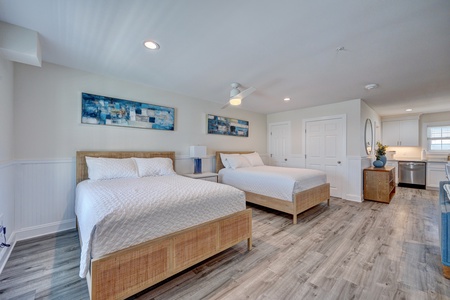 Your spacious bedroom offers twin beds with crisp linens, modern coastal decor, and an open-concept kitchen for ultimate convenience.