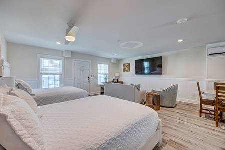 Unwind in your spacious room with two plush beds, cozy seating area, and modern amenities for the perfect retreat.