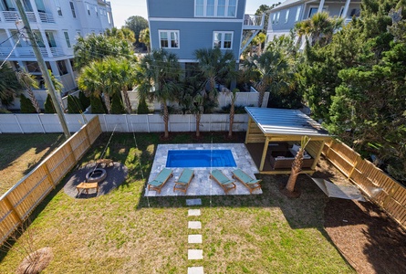 Aerial view of the private backyard featuring a sparkling pool, lounge chairs, and covered pavilion surrounded by tropical landscaping.