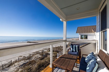 Stunning beachfront balcony with comfortable seating offers sweeping ocean views and direct beach access for your perfect coastal getaway.