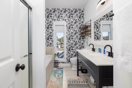 You'll love this stylish bathroom with tropical wallpaper, dual sinks, and thoughtful touches that make your morning routine feel luxurious.