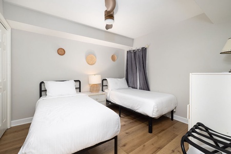 Relax in this serene twin bedroom with crisp white linens, warm wood floors, and thoughtful decor that creates your perfect retreat.