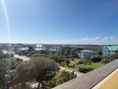 Elevated coastal community with scattered homes and lush greenery under clear blue skies.