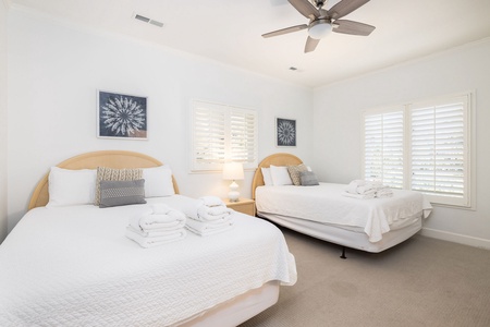 Rest comfortably in your two queen bed retreat with a ceiling fan and coastal artwork creating the perfect peaceful sanctuary
