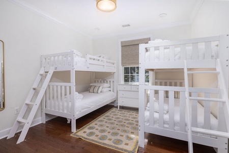 Your kids will love this bright bunk room with comfortable sleeping spaces for four, featuring cozy white linens and playful décor.