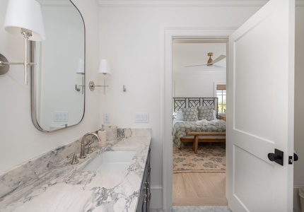 Step into your elegant en-suite bathroom with marble counters, where soft lighting creates a spa-like atmosphere before retreating to your cozy bedroom.
