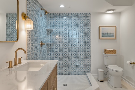 Soak in your elegant bathroom featuring a stunning walk-in shower with beautiful blue patterned tiles and luxurious brass fixtures.