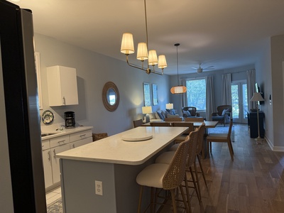 Your open-concept space flows beautifully from kitchen to living room, with warm lighting and modern furnishings creating the perfect atmosphere for relaxing or entertaining.