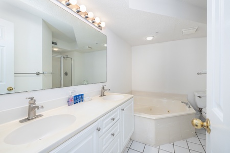 The primary en suite bathroom has a large jacuzzi tub and glass walk-in shower
