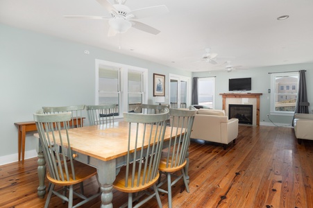 Relax in your spacious open-concept living space featuring warm hardwood floors, cozy fireplace, and stunning ocean views through floor-to-ceiling windows.