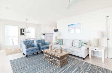 Cozy living space with comfortable sofas, coastal décor, and a seamless flow to the kitchen and dining area