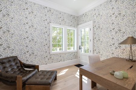 Upstairs you'll find this wallpapered sitting room with a leather arm chair and wooden writing desk