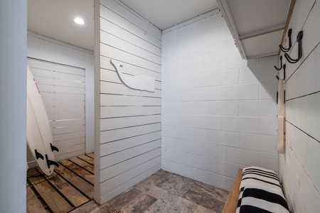 A dedicated outdoor shower with shiplap walls and a teak floor grate offers the perfect post-beach retreat