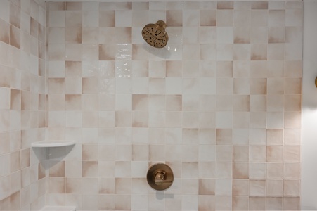 Step into your private shower featuring elegant textured tiles and brass fixtures for a luxurious, spa-like experience.
