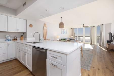 Your sleek white kitchen flows into a bright living space with stunning views through floor-to-ceiling windows.