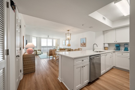 Sunlight streams through your open-plan kitchen and dining space, where white countertops and warm hardwood create a perfect gathering spot.