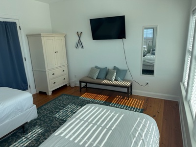 Relax in your bright bedroom with comfortable seating, wall-mounted TV, and plenty of storage in the white armoire.