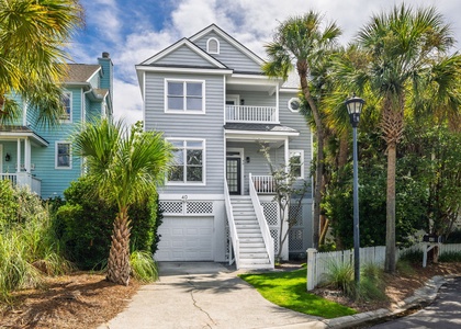 Charming coastal home with classic beach architecture, palm trees, and elevated entryway just steps from the shore