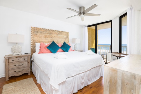 The primary bedroom features a king size bed and large windows overlooking the beach