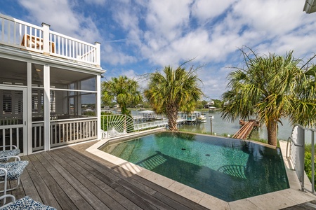 Sparkling pool with waterfront views, framed by swaying palms and a spacious deck—perfect for morning swims and sunset relaxation by the water.