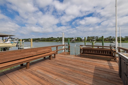 Private waterfront dock with built-in seating where you can watch boats drift by and enjoy peaceful views across the tranquil waterway to tree-lined shores.