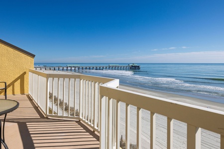 Oceanfront balcony with stunning beach views and pier backdrop for perfect coastal relaxation.