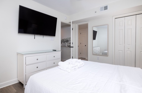 Rest peacefully in your bright, modern bedroom featuring crisp white linens, entertainment center, and ample storage space for all your belongings.