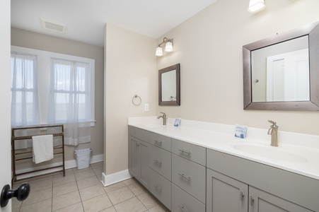 Refresh in your spacious bathroom with dual vanities, pristine white countertops, and abundant natural light streaming through crisp windows.