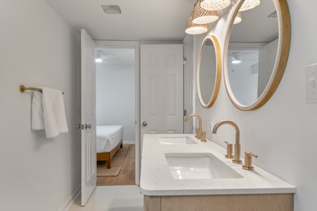 Step into your elegant ensuite with dual vanities, gold fixtures, and modern design that connects seamlessly to your bedroom retreat.