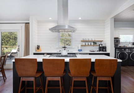 Modern coastal kitchen with stainless appliances, bar seating, and everything you need to prepare meals after a day at the beach.