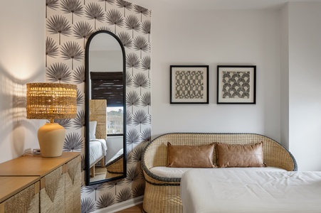 Sink into this stylish retreat where tropical wallpaper and wicker textures create your perfect sanctuary for rest and relaxation.