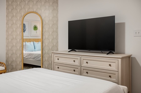 Your elegant bedroom features a large flat-screen TV and stylish dresser, perfect for unwinding after your adventures.