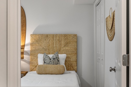 Sink into crisp white linens beneath your stunning woven headboard, where tropical textures and coastal charm create your perfect retreat.
