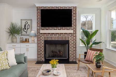 Cozy up by your fireplace while enjoying your favorite shows on the wall-mounted TV in this bright, plant-filled living space.