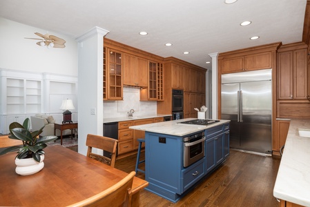 Your fully equipped gourmet kitchen features rich wood cabinetry, a stylish blue island with built-in cooking, stainless appliances, and ample space for memorable meals together.