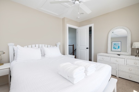 Rest peacefully in your bright bedroom with plush white linens and coastal charm.
