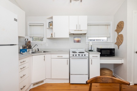 A bright, airy kitchen awaits with crisp white cabinets, full appliances, and natural light streaming through the windows—perfect for whipping up your morning coffee or a fresh meal during your stay.