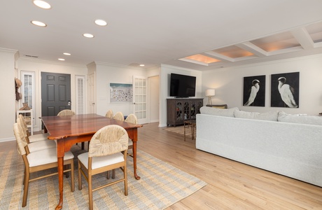 Relax in your spacious open-plan living area featuring coastal artwork, warm wood floors, and elegant dining space perfect for memorable meals together.